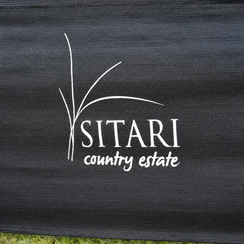 Close-up of white Sitari Country Estate logo printed on black woven shade net showing the print and fabric texture.